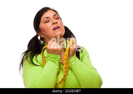 Attraktive frustriert Hispanic Frau mit Maßband vor einem weißen Hintergrund. Stockfoto