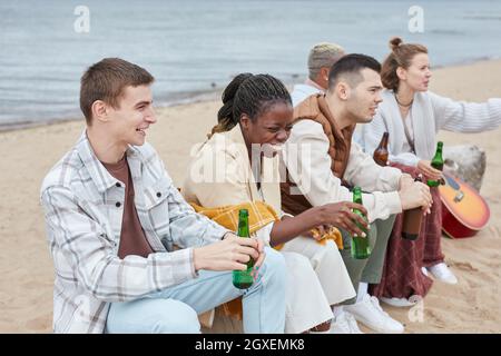 Vielfältige Gruppe junger Leute, die im Herbst am Strand campen und gemeinsam im Freien Spaß haben Stockfoto