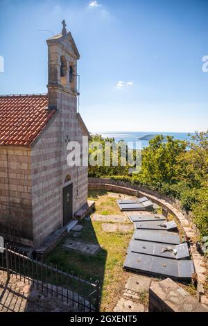 Podostrog, Budva - 23. September 2021: Kirche des heiligen Johannes des Theologen und Friedhof in der Nähe, Podostrog, Budva, Montenegro Stockfoto