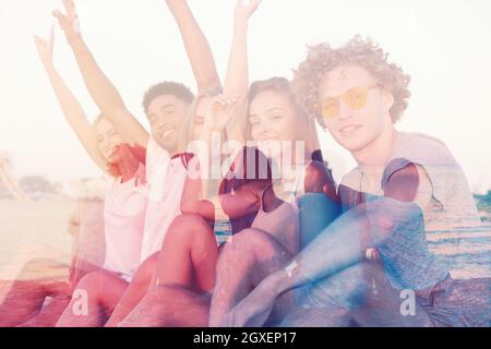 Gruppe von glücklichen Freunden, die Spaß am Meeresstrand in der Dämmerung haben. Doppelbelichtung Stockfoto