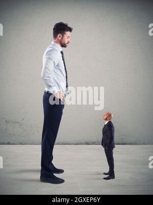 Kleiner Geschäftsmann, erschreckt von seinem großen Chef im Büro Stockfoto