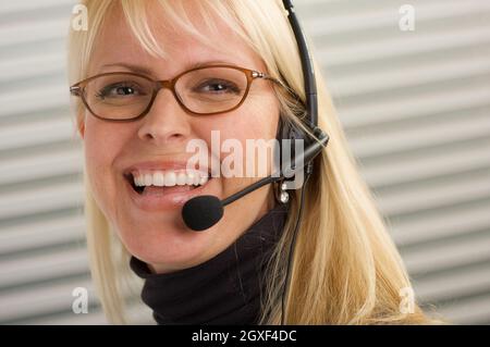 Attraktive Geschäftsfrau Gespräche über ihr Handy Kopfhörer. Stockfoto