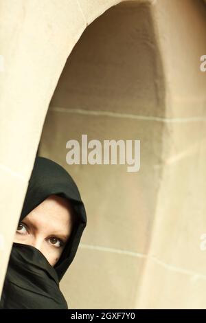 Vorsichtige islamische Frau in einer Fensterscheibe, die traditionelle Burka oder Niqab tragen. Stockfoto