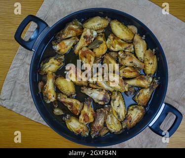 Knoblauch-Hühnerflügel (Pollo al ajillo). Spanisches Tapas-Gericht in einer Pfanne auf einer Serviette. Draufsicht Stockfoto