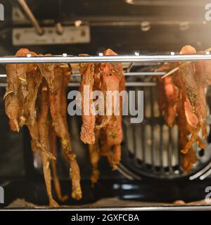 Hühnerfleisch trocknet auf dem Grill im Ofen in der heimischen Küche, Nahaufnahme Stockfoto