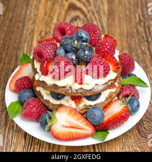 Pfannkuchen mit Schlagsahne und frischen Beeren auf dem Holztisch Stockfoto