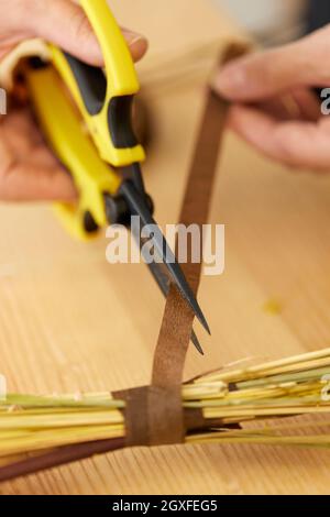 Aus nächster Nähe macht der Blumenhändler mit einer Schere einen Strauß getrockneter Blumen. Stockfoto