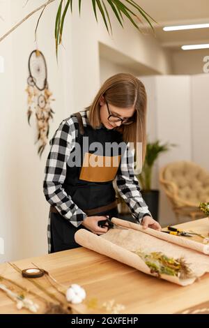 Floristin Frau macht schöne Bouquet von getrockneten Blumen auf Holz Tabelle Stockfoto