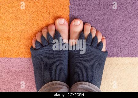 Bunion, Hallux valgus. Finger Toe Separator Socken auf Füßen isoliert auf bunten Teppich. Stockfoto