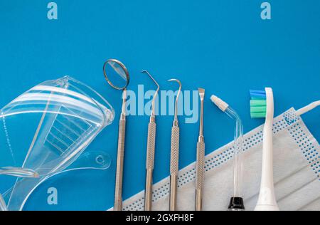 Zahnarztwerkzeuge auf blauer Oberfläche aus nächster Nähe. Professionelle Reinigungswerkzeuge für die Zahnhygiene. Zahnstein- und Plaque-Entferner-Set, Dental Scaler und Mundspiegel in Stockfoto