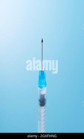 Spritze auf blauem Hintergrund platziert. Impfkonzept Stockfoto