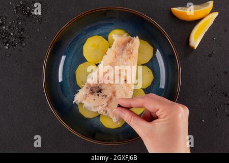 Gegrilltes Fischfilet mit Kartoffeln und Lavasalz auf dunklem Hintergrund. Stockfoto