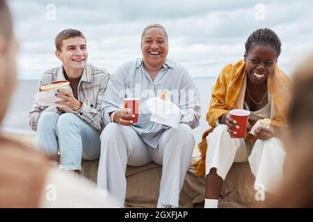 Offene Aufnahme einer Gruppe von Freunden, die beim Picknick am Strand lachen Stockfoto