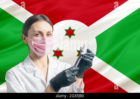 Die Ärztin bereitet die Impfung vor dem Hintergrund der Burundi-Flagge vor. Impfkonzept Burundi. Stockfoto