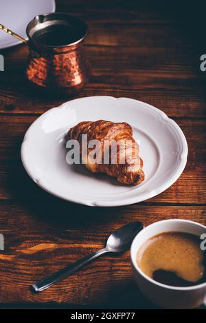 Tasse türkischer Kaffee und Croissant auf weißem Teller für Frühstück Stockfoto