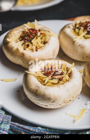 Champignons gefüllt mit geriebenem Cheddar-Käse und Gewürzen Stockfoto