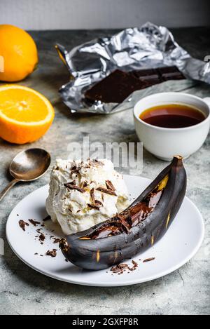 Süßes Dessert. Gegrillte Banane mit dunkler Schokolade, Zitronensaft und Vanilleeis. Stockfoto