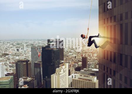 Geschäftsmann steigt mit einem Seil in ein hohes Gebäude. Konzept der Bestimmung Stockfoto