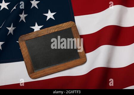 Nahaufnahme alten Vintage Schieferkreide Schild in Holzrahmen auf Baumwolle bestickt US-Nationalflagge Hintergrund, Symbol des amerikanischen Patriotismus, erhöht Stockfoto