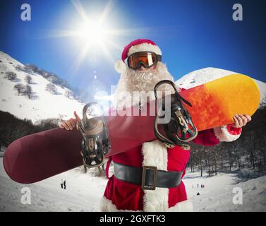 Weihnachtsmann mit Snowboard in den Bergen Stockfoto