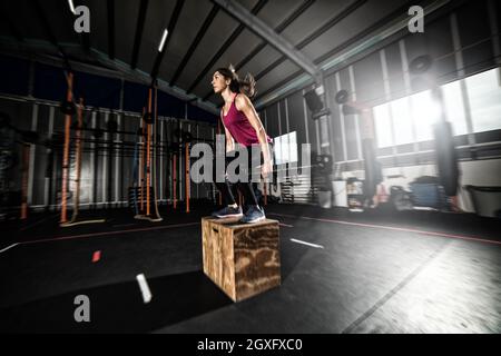 Entschlossenes athletisches Mädchen macht Boxsprungübungen im Fitnessstudio Stockfoto