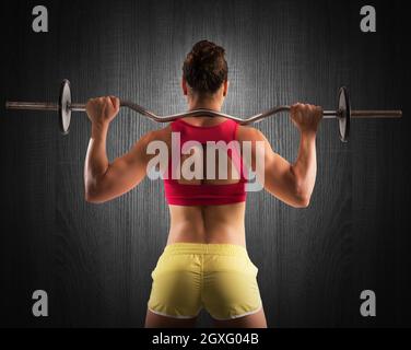 Muskulöse Frau, die einen Outrigger mit Gewichten hebt Stockfoto
