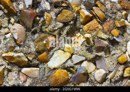 Eine raue Kieselsteindecke an einer Außenwand, die kleine Steine in verschiedenen Formen und Farben zeigt Stockfoto