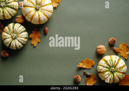 Happy Thanksgiving Day Konzept. Herbstkomposition mit reifen Kürbissen, gefallenen Blättern, Walnüssen, Eicheln auf vintage-grünem Hintergrund. Flach liegend, Draufsicht, Stockfoto