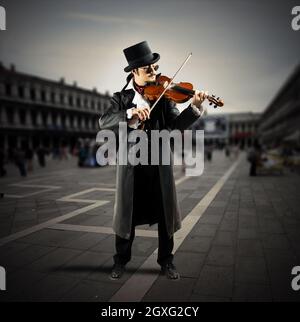 Der Geiger spielt auf einem Platz mit Menschen, die gehen Stockfoto