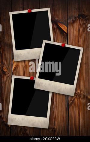 Nahaufnahme von drei leeren Polaroid Instant-Bilderrahmen, die auf einem alten grunge-braunen Holzwandhintergrund fixiert sind, niedriger Winkel, Seitenansicht Stockfoto