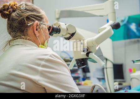 Zahnärztliche Behandlung mit einem Mikroskop. Mann, der Zähne bei Zahnärzten untersucht hat. Termin beim Zahnarzt. Lifestyle, echtes Leben Stockfoto