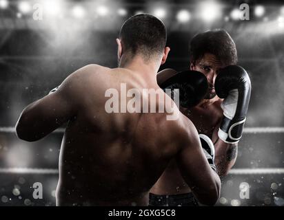 Boxer in einem Boxenwettbewerb schlägt seinen Gegner mit einem Schlag Stockfoto