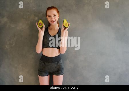 Athletisches Mädchen mit Turnbekleidung isst Avocado Stockfoto