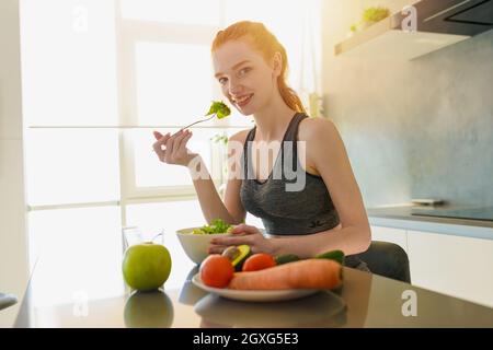 Athletic Mädchen mit Turnhalle Kleidung isst Salat Stockfoto