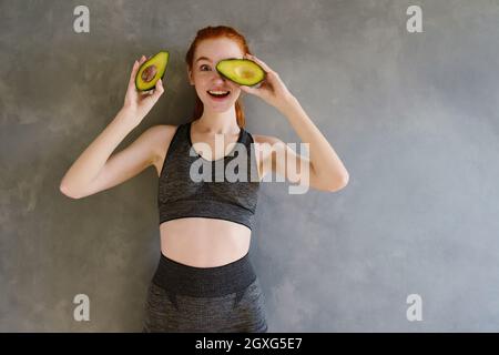 Athletisches Mädchen mit Turnbekleidung isst Avocado Stockfoto