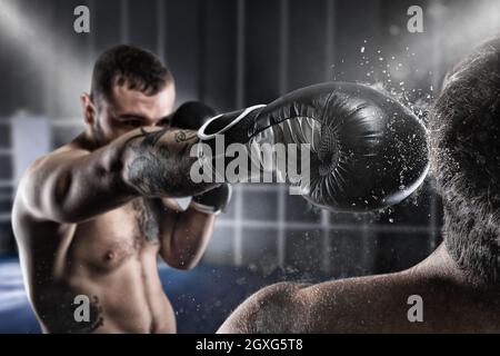 Boxer in einem Boxenwettbewerb schlägt seinen Gegner mit einem Schlag Stockfoto