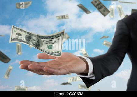 Geschäftsmann mit verregneten Dollarnoten über dem Himmel. Konzept von Erfolg, Karriere und großem Einkommen Stockfoto