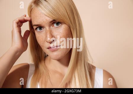 Nahaufnahme des Porträts einer jungen schönen Frau mit Sommersprossen, die im Studio auf pastellfarbenem Hintergrund posiert Stockfoto