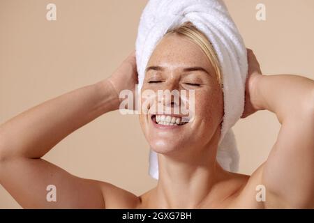 Studioportrait einer jungen schönen Frau, die ein weißes Handtuch auf ihren Kopf gewickelt hat Stockfoto