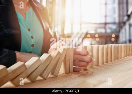 Geschäftsfrau hält eine Kette fallen wie Domino Spiel Spielzeug. Konzept zur Vermeidung der Krise und Ausfall im Geschäft Stockfoto