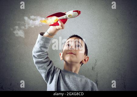 Kind spielt mit einer kleinen Rakete. Konzept der Phantasie Stockfoto