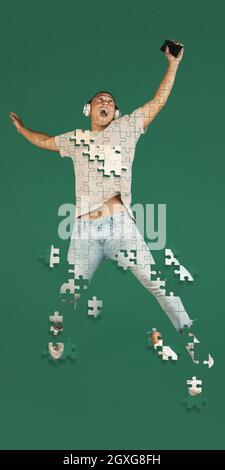 In voller Länge kreative Collage von Mann Musik in einem Sprung isoliert über grünen Hintergrund hören. Portrait bestehen aus Puzzleteilen Stockfoto