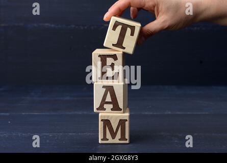 Weibliche Hand hält einen Stab mit dem Inschrift-Team auf blauem Hintergrund. Talentsuchkonzept, Rekrutierung für Unternehmen. Headhunting Stockfoto