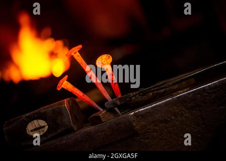 Nahaufnahme heißer Metallnagel auf einem Amboss in der Schmiedewerkstatt Stockfoto