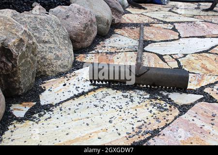 Ein Regal, das verwendet wird, um schwarze Kieselsteine zwischen Terrassensteinen zu platzieren. Stockfoto