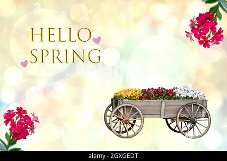 Hallo Frühlingskarte. Fröhlicher Frühling oder Grußkarte Design mit einem alten dekorativen großen Holzwagen mit vielen bunten Blumen und dem Hallo Frühling Text ov Stockfoto
