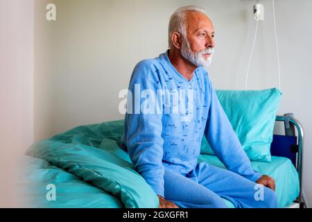Älterer männlicher Patient im Krankenhausbett, der sich von der Krankheit erholt. Gesundheitskonzept. Stockfoto