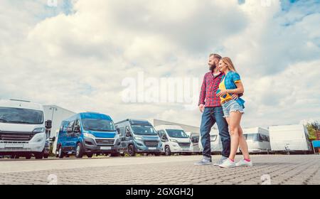 Frau und Mann, die Wohnmobil zum Mieten oder Kaufen auf dem Hof des Händlers wählen Stockfoto