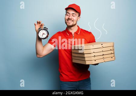 Courier ist pünktlich, um Pizzen zu liefern. Cyanfarbener Hintergrund Stockfoto