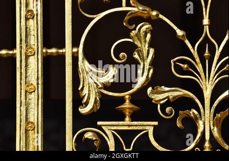 Eine Nahaufnahme von goldverzierten Metallarbeiten an Palasttoren vor schwarzem Hintergrund Stockfoto